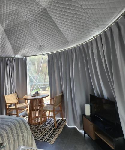 a bedroom with a bed and a tv and a table at River Glamping Kalopanayiotis in Kalopanayiotis