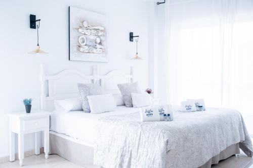 a white bedroom with a white bed with pillows at Mare Estepona Hotel in Estepona