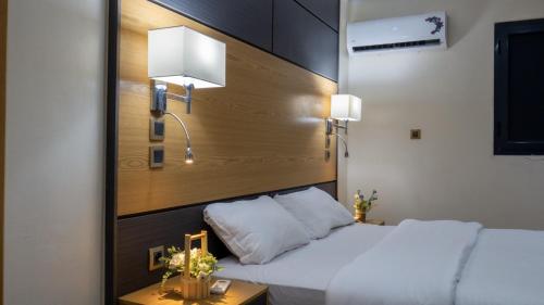 a bedroom with two beds and a headboard with a lamp at Complexe Hôtelier Sabah in Nouakchott