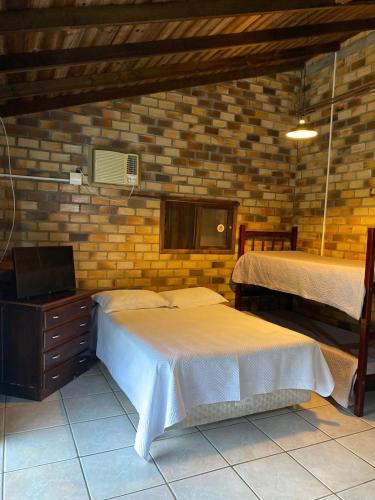 1 dormitorio con 2 camas y TV. en Residencial da Casinha, en Garopaba