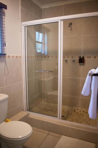 a shower with a glass door in a bathroom at African Sands B&B in Amanzimtoti