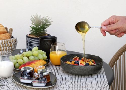 a person pouring a spoon into a bowl of breakfast food at Arxegono Cave Houses Santorini in Pirgos