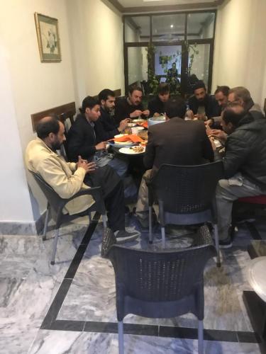 un grupo de hombres sentados alrededor de una mesa comiendo comida en SWAT HILL VIEW RESORT- only for families, en Swat