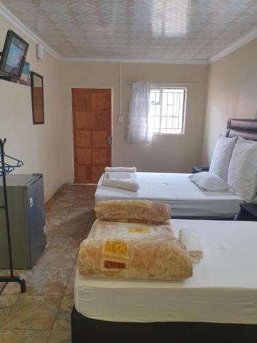 a bedroom with two beds and a window at HostHub Guest House in Rustenburg