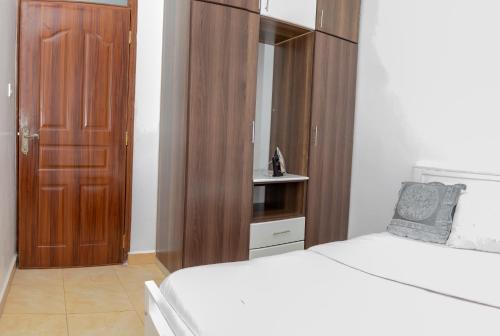 a bedroom with a bed and a wooden cabinet at House of L in Eldoret
