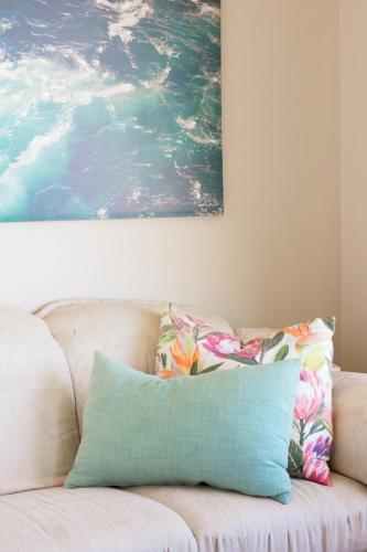 a couch with two pillows sitting under a painting at African Sands B&B in Amanzimtoti