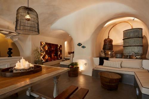 a living room with a table and a couch at Arxegono Cave Houses Santorini in Pirgos
