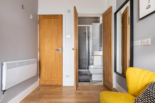 a bathroom with a yellow chair and a toilet at Stunning studio flats in Penge in Sydenham