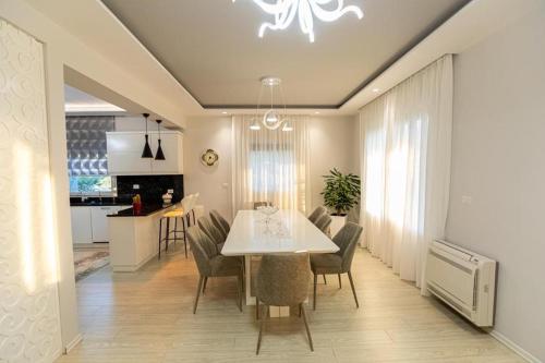 a dining room and kitchen with a white table and chairs at VILA LLANO in Vlorë