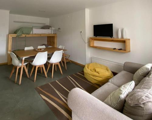 een woonkamer met een bank en een tafel en stoelen bij Natagonia Apartments in Puerto Natales