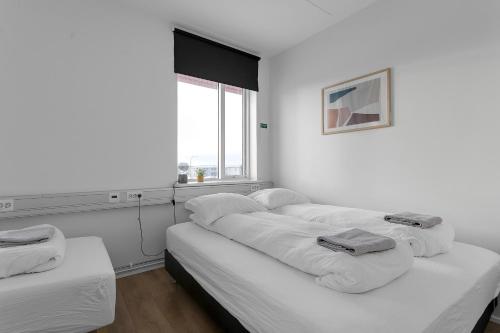 een witte kamer met 3 bedden en een raam bij Bank Guesthouse by KEF Airport in Keflavík