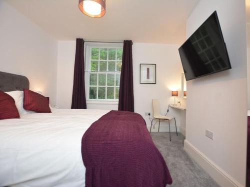um quarto com uma cama branca e uma televisão em Home from Home - Greenwich House em Chester