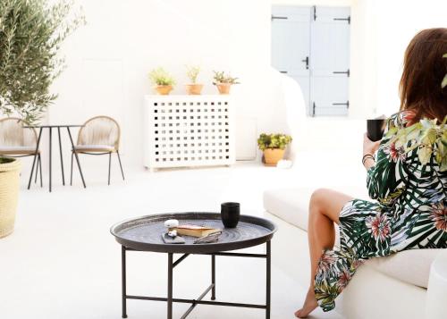 a woman sitting on a couch in a living room with a table at Arxegono Cave Houses Santorini in Pirgos