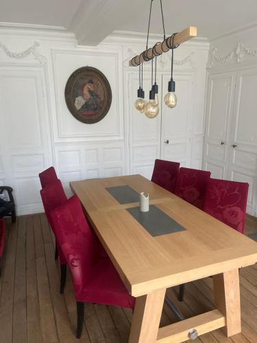 a dining room with a wooden table and red chairs at La collégiale in Beauvais