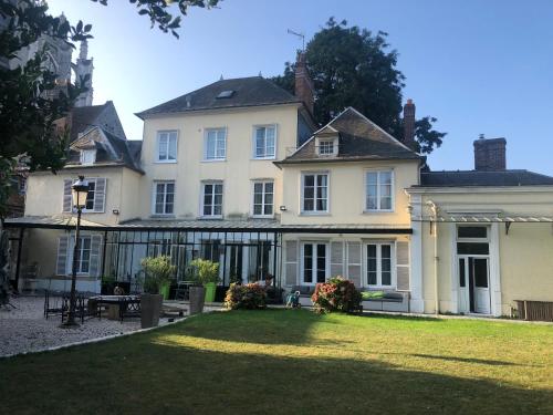 una gran casa blanca con césped delante en La collégiale en Beauvais