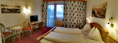 a hotel room with a bed and a desk and a television at Hotel Landhaus Zillertal in Fügen