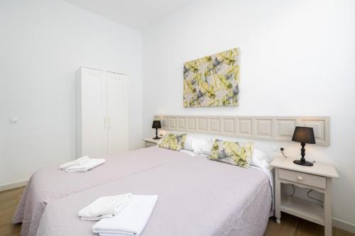 um quarto branco com uma cama e uma secretária com um candeeiro em Apartamento Jazmín em Málaga