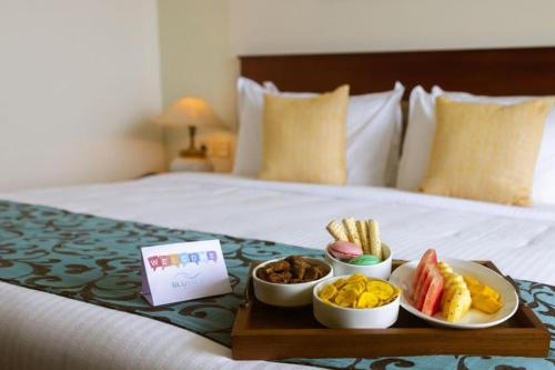 a tray with three bowls of food on a bed at Waters Edge Kochi - a VKation Experience in Cochin