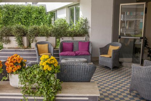 a patio with wicker chairs with colorful pillows at Hotel Enterprise in Montalto di Castro