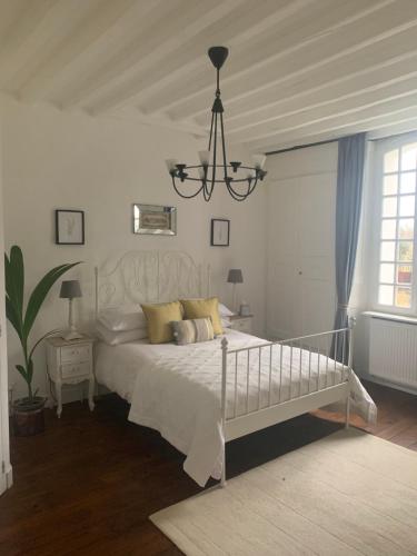 a bedroom with a white bed and a chandelier at La Maison Du Pont in La Rochebeaucourt-et-Argentine