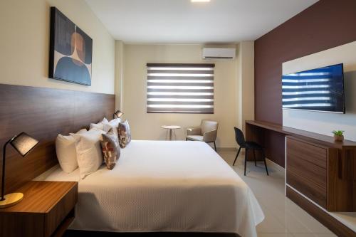 a bedroom with a large white bed and a desk at Equipetrol Suites apart hotel in Santa Cruz de la Sierra