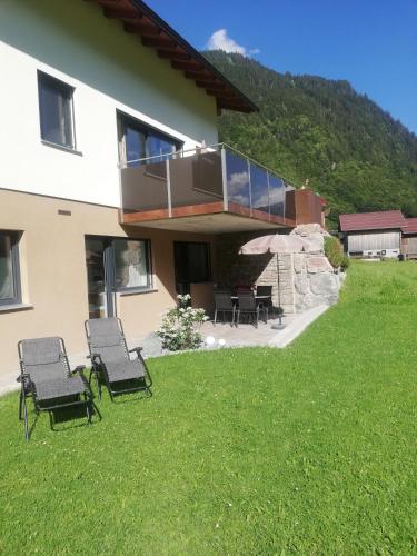 a house with chairs on the lawn in front of it at Appart Stefanie in Sankt Gallenkirch