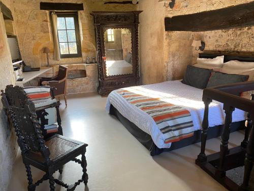 a bedroom with a bed and a mirror and a chair at Manoir La Barriere - Lot in Le Vigan
