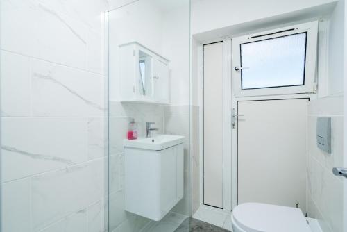 Baño blanco con aseo y lavamanos en Private Room in London Enfield with parking, en Enfield