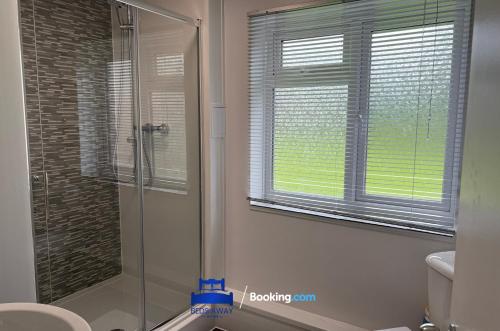 a bathroom with a shower and a toilet and a window at 3 Bedroom Cosy Bungalow By Beds Away Short Lets & Serviced Accommodation Chalgrove With Outdoor Dining Area 