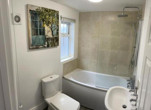 a bathroom with a tub and a toilet and a sink at Stylish cottage - Parking for 2 cars! in Lincolnshire
