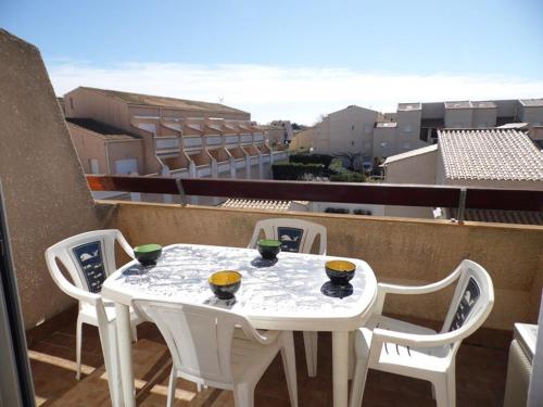 une table blanche et des chaises sur un balcon dans l'établissement Charmant T2 climatisé avec mezzanine, terrasse et piscine, idéal pour 4-6 personnes - FR-1-326-430, à Le Castellas
