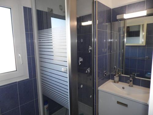 une salle de bain carrelée bleue avec un lavabo et une douche dans l'établissement Charmant T2 climatisé avec mezzanine, terrasse et piscine, idéal pour 4-6 personnes - FR-1-326-430, à Le Castellas