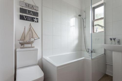 a bathroom with a toilet and a tub and a sink at Promenade Apartments Maldon in Maldon