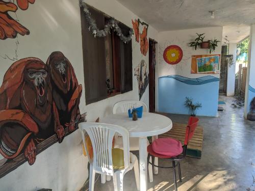 einen Tisch und Stühle in einem Zimmer mit Gemälden an der Wand in der Unterkunft Palomino EcoHouse & Camping in Palomino