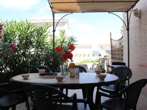 une table et des chaises assises sur une terrasse dans l'établissement Maison de Vacances avec Piscine et Terrasse, 800m de la Plage - 6 Couchages, Saint Pierre la Mer - FR-1-229D-82, à Fleury