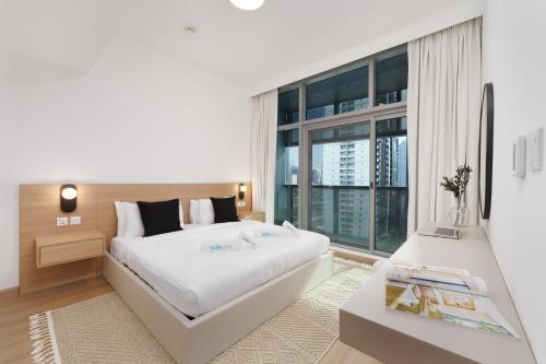 a bedroom with a large white bed and a large window at Luxe Living in our Exquisite 1 Bedroom Apartment in Dubai