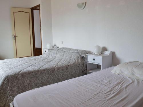 - une chambre blanche avec 2 lits et un miroir dans l'établissement Maison climatisée 4 pièces, 8 couchages, proche plage et commerces, avec véranda et barbecue - FR-1-229D-113, à Fleury