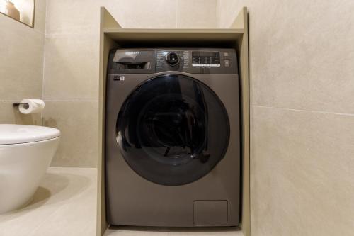 a washing machine in a bathroom next to a toilet at Luxe Living in our Exquisite 1 Bedroom Apartment in Dubai