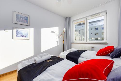 two beds with red pillows in a room at ApartamentyGdansk EU Marina Primore in Gdańsk