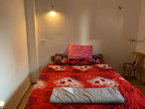 Schlafzimmer mit einem Bett mit einer roten Bettdecke in der Unterkunft AMFIBIANHouse in Dahab
