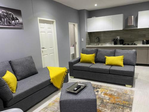 a living room with a couch and yellow pillows at Ongwe Complex - Holiday Apartment in Swakopmund