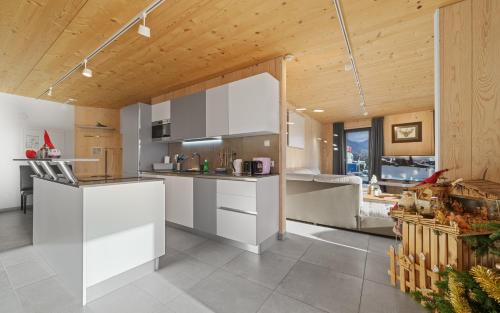 a kitchen with white cabinets and a wooden ceiling at Aparthotel Zell am See (Contactless Check-In) in Zell am See