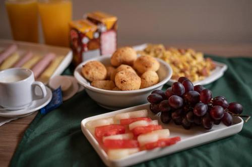 a table with two plates of food and a bowl of fruit at Motel Stilo - Adults Only in Contagem