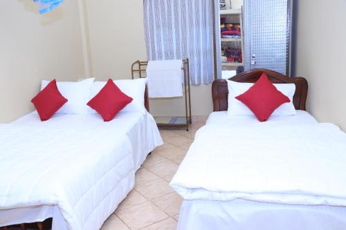 two beds with red pillows in a room at Archu Agam in Kotagala