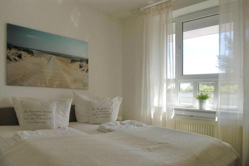 een witte slaapkamer met een bed met kussens en een raam bij Ferienwohnung De Diek 103 in Dorum