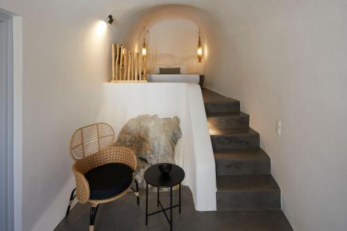 a room with a staircase with chairs and a table at Arxegono Cave Houses Santorini in Pirgos