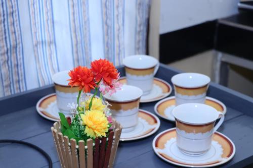 uma mesa com quatro chávenas e um vaso de flores em Archu Agam em Kotagala