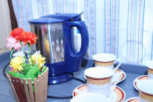 a blue coffee pot and a vase of flowers on a table at Archu Agam in Kotagala