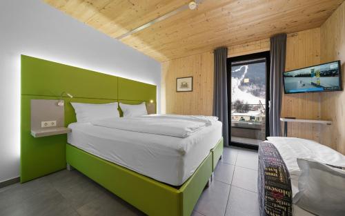 a bedroom with a large bed with a green headboard at Aparthotel Zell am See (Contactless Check-In) in Zell am See