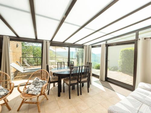 une salle à manger avec une table, des chaises et des fenêtres dans l'établissement Appartement Soleil levant 4 à 5 Personnes, à Millau